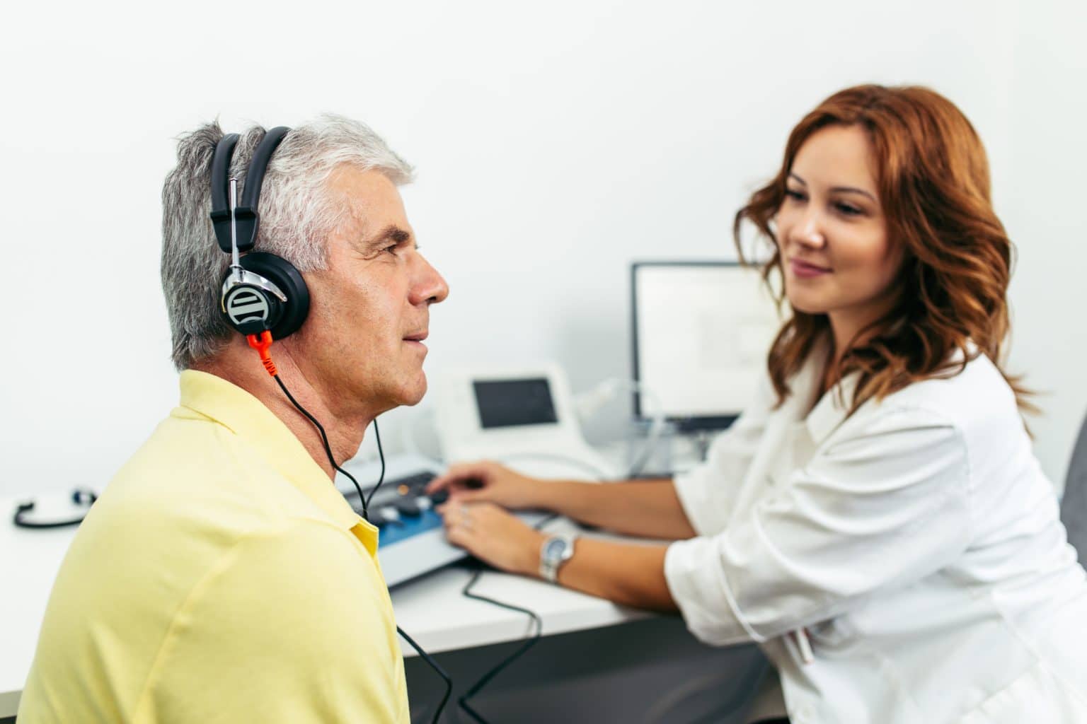 audiology patient completing hearing test Patient with headphones on gets tested for hearing loss by an audiologist